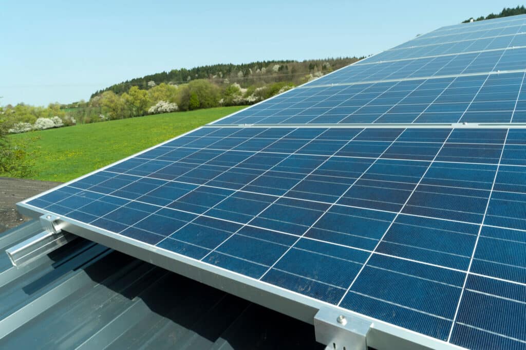 Auf diesem Bild sind Solaranlagen zu sehen. Im Hintergrund ist ein grünes Feld zu sehen.